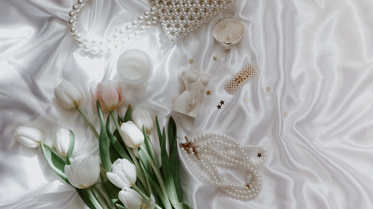 An collection of potential gift ideas, roses, pearl bag, seashells, and jewelry.